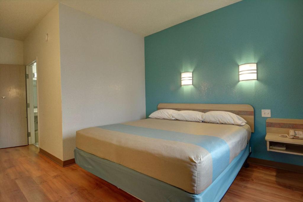 a bedroom with a bed with two lights on the wall at Motel 6-Denison, TX in Denison