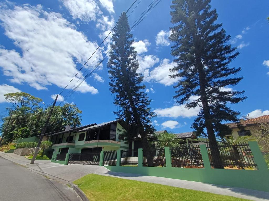 a house on a street with two tall trees at Casa inteira 3 quartos Centro em Pomerode in Pomerode