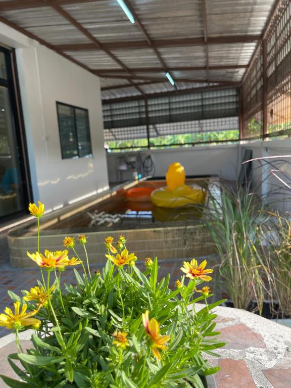 un jardin avec un bac à fleurs jaunes au premier plan dans l'établissement ท่าบูรพาวิลล่า ที่พักพร้อมสระน้ำ ทั้งหลัง, à Ban Hua Khao Sammuk