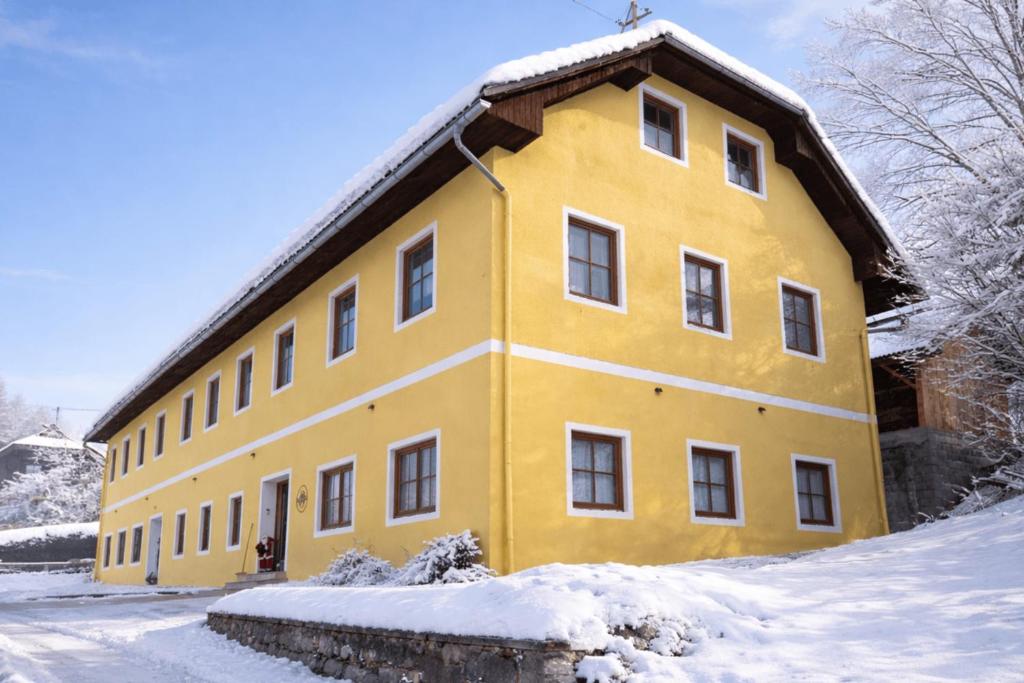 un edificio giallo con neve per terra di Haus Waldbach - nahe Nassfeld - Pressegger See a Köstendorf