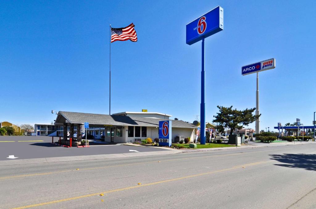 una gasolinera con una bandera americana en un poste en Motel 6-Willows, CA, en Willows