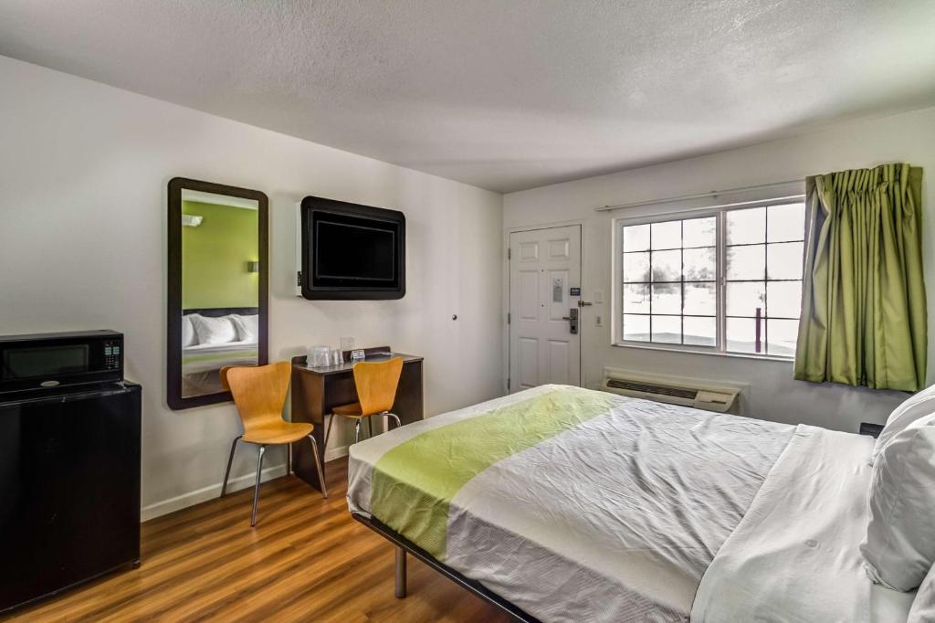 a bedroom with a bed and a desk and a television at Motel 6-Visalia, CA in Visalia