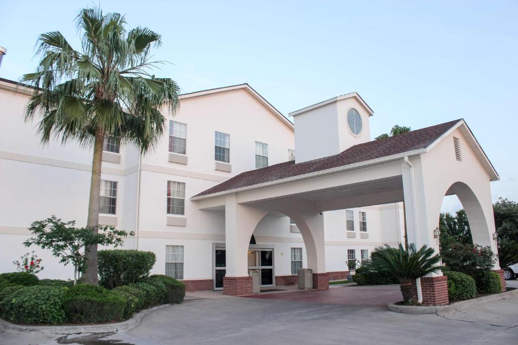 un grand bâtiment blanc avec un palmier en face dans l'établissement Motel 6-Rosenberg, TX, à Rosenberg