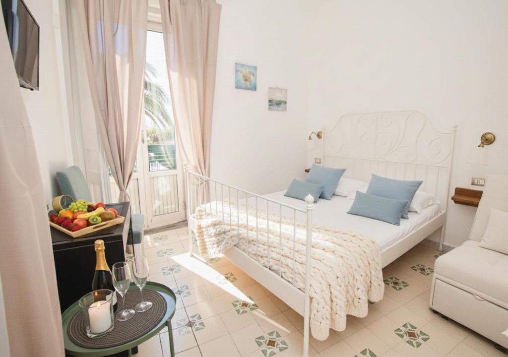 een witte slaapkamer met een bed en een tafel met een fruitschaal bij Domus Linda B&B in Ischia