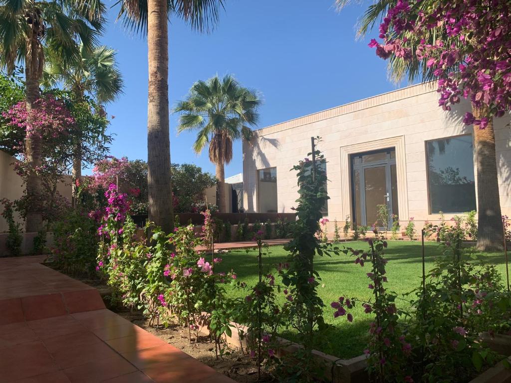 a garden with palm trees and flowers in front of a building at فيلا المنزل in Makkah