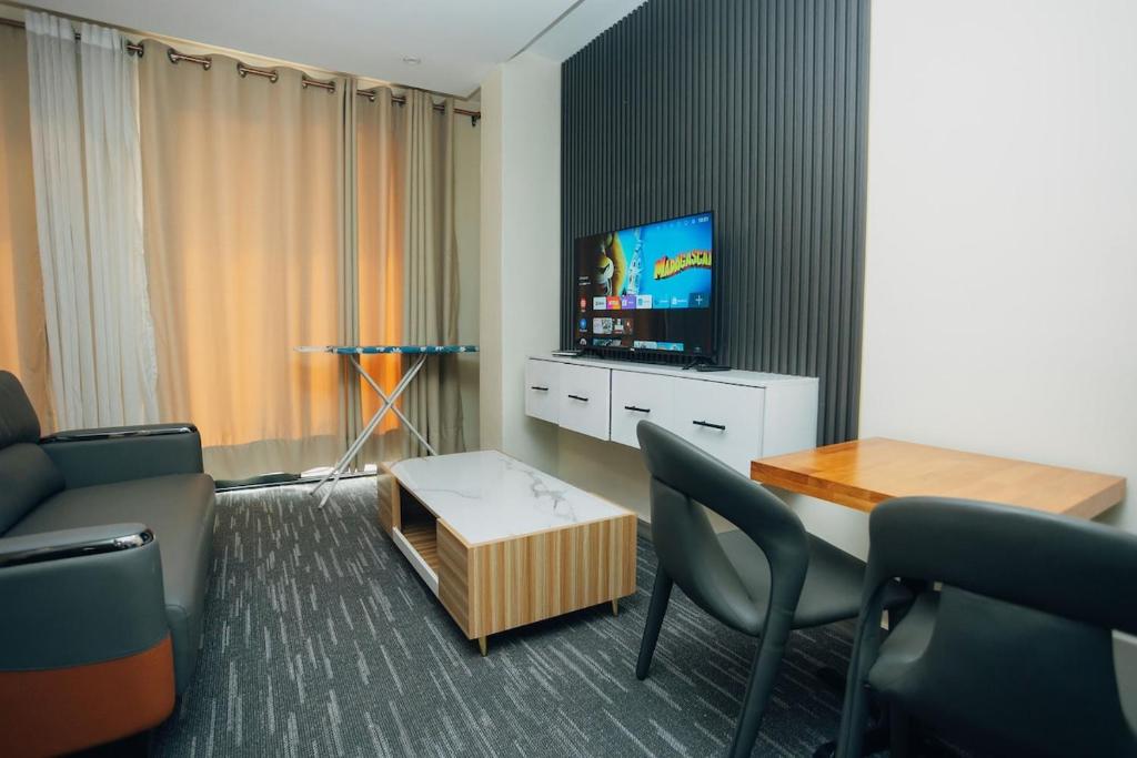 un salon avec un canapé, une table et une télévision dans l'établissement Glands Ndera f04, à Kigali