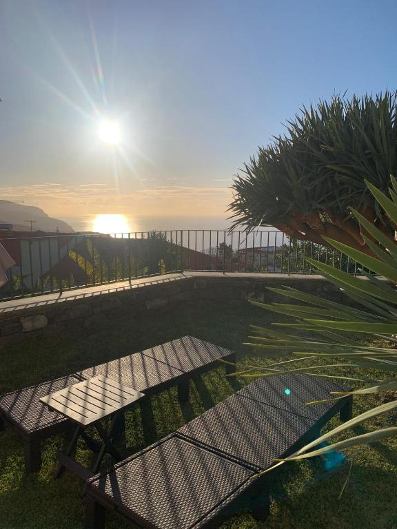 a table and benches in the grass with the sun at Namastê House II in Funchal