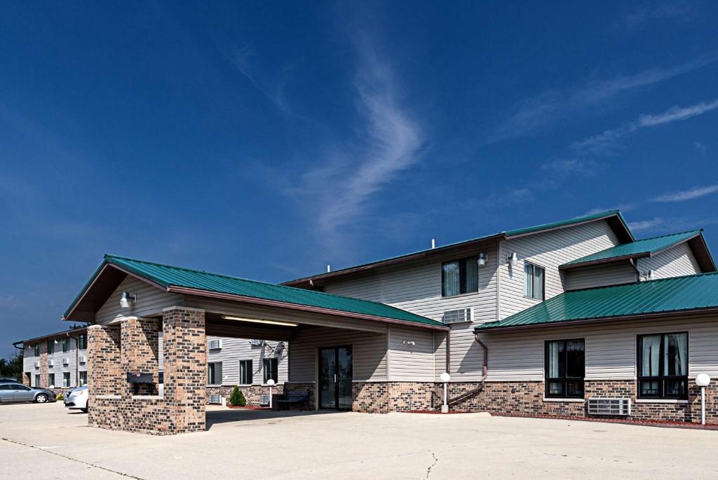 a white building with a green roof and a parking lot at Motel 6-Kewanee, IL in Kewanee