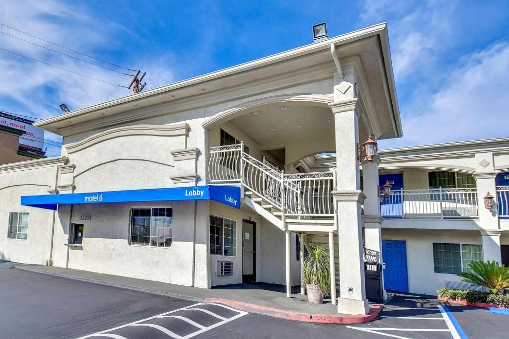 Motel 6 Garden Grove في أنهايم: مبنى أبيض مع شرفة على شارع