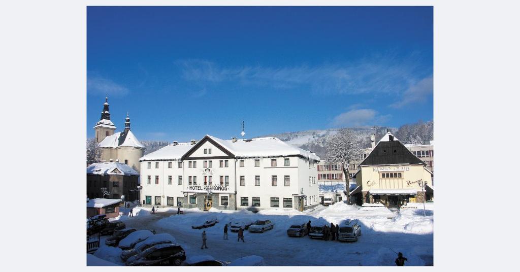een groot wit gebouw met sneeuw op de grond bij Hotel Krakonos in Rokytnice nad Jizerou