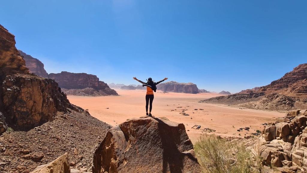 a person standing on a rock in the desert at Desert Life Camp Wadi Rum in Wadi Rum