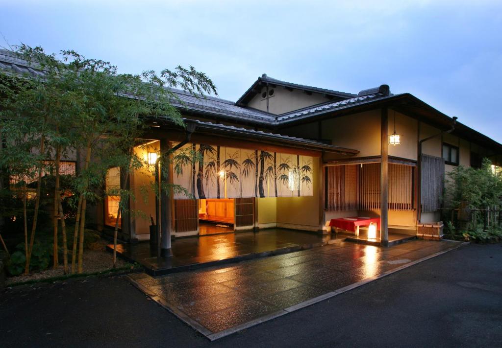 a house in the rain with a bench in front of it at 御宿竹林亭 in Takeo