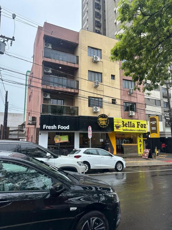 two cars parked on a street in front of a building at Apartamentos Nadai 201 in Foz do Iguaçu