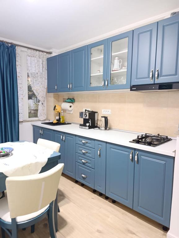 a kitchen with blue cabinets and a table with chairs at Apartament Karina in Baia Mare