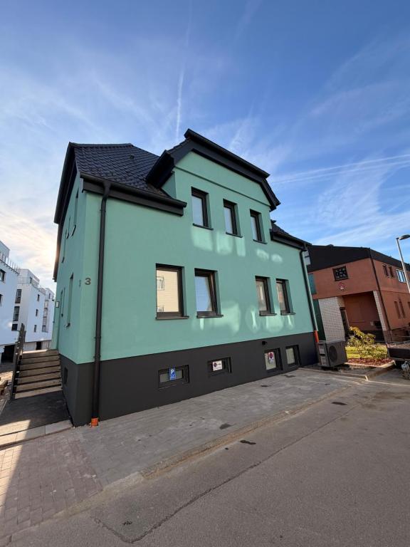 un bâtiment vert avec un toit noir dans une rue dans l'établissement Pension Elisa, à Bad Friedrichshall