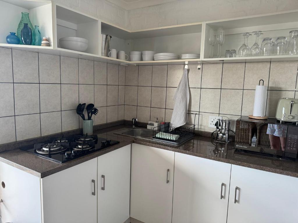 een keuken met witte kasten en een aanrechtblad bij Pebbles & Shells in Kleinmond