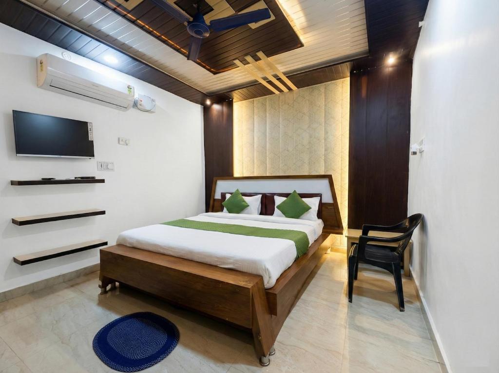 a bedroom with a bed and a tv and a chair at Guru Amrit Residency & Guru Kripa Guest house in Ayodhya