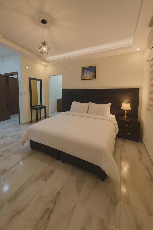 a bedroom with a large white bed and a lamp at I cloud Petra hostel in Wadi Musa
