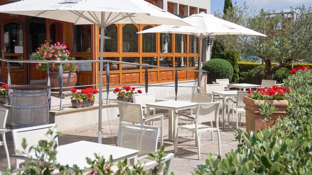 eine Gruppe von Tischen und Sonnenschirmen vor einem Gebäude in der Unterkunft Hotel Montero in Mondoñedo