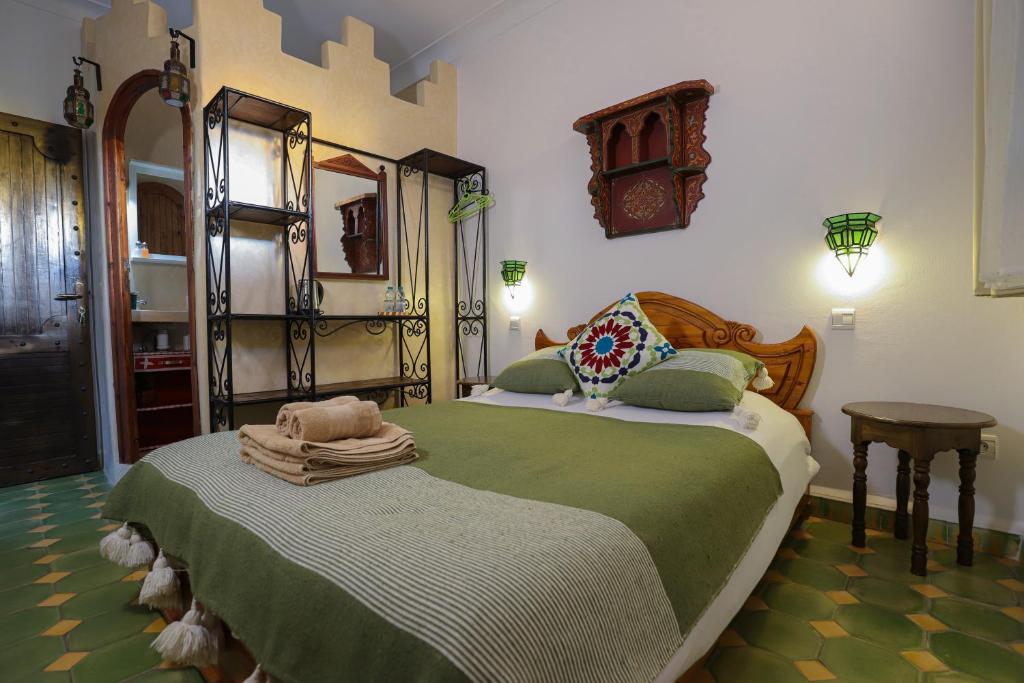 une chambre avec un lit avec une couette verte dans l'établissement Riad Salmiya Dune, à Essaouira