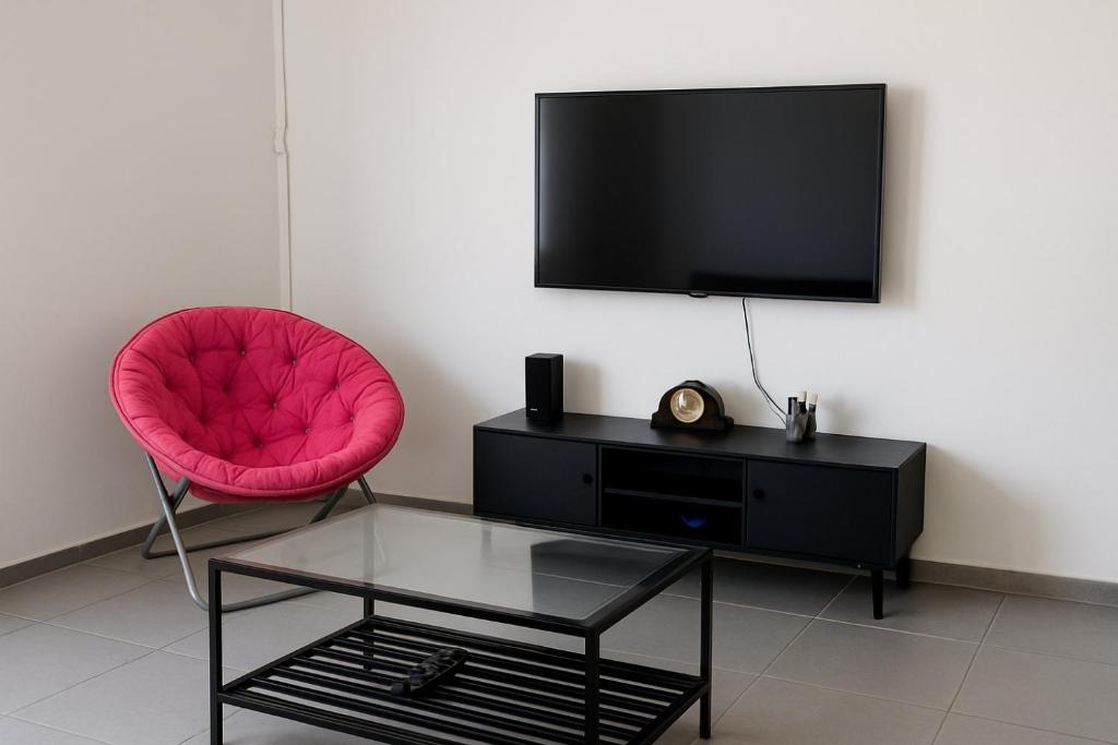 a living room with a pink chair and a television at Ocean view apart in Tel Aviv