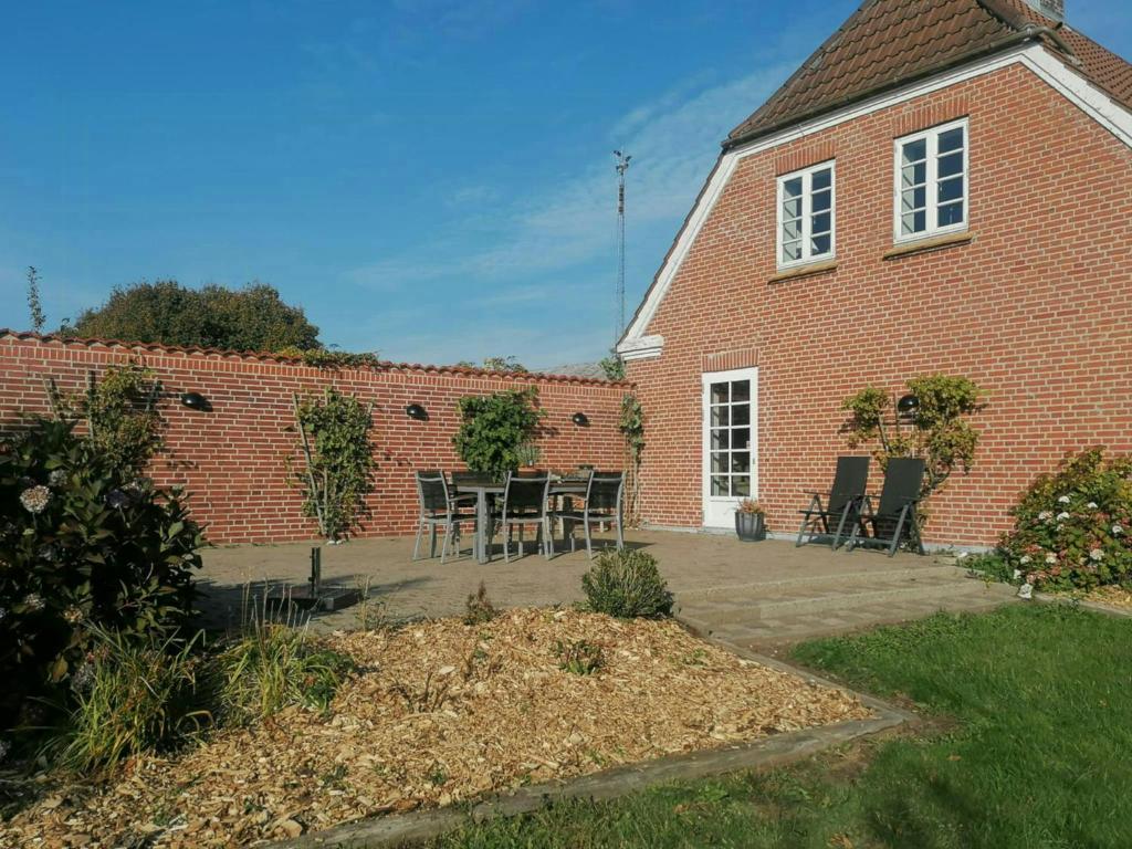 ein Backsteingebäude mit einer Terrasse mit einem Tisch und Stühlen in der Unterkunft Nature Gem Near Haderslev With 160-Year-Old Beech in Vedbøl