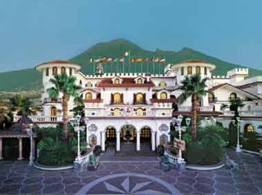 ein großes Gebäude mit Palmen davor in der Unterkunft Grand Hotel La Sonrisa in SantʼAntonio Abate