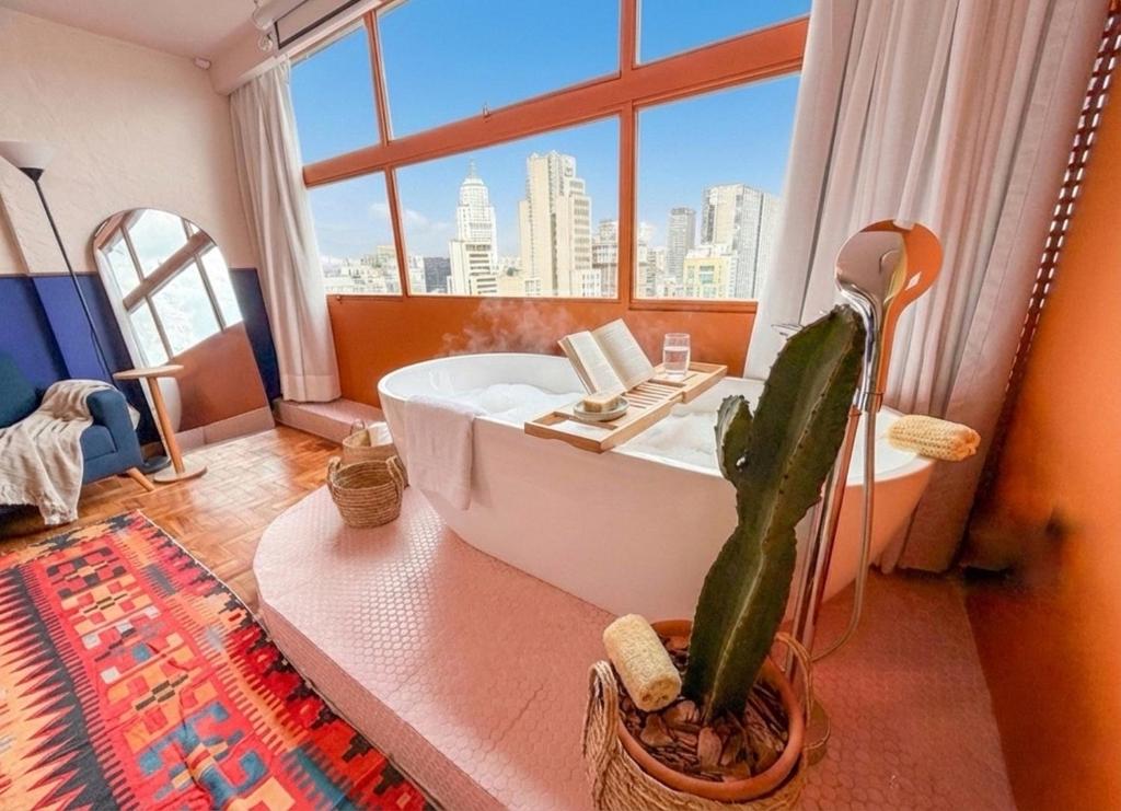 une salle de bains avec un cactus et une baignoire avec une fenêtre dans l'établissement Vem pro Mirante, à São Paulo