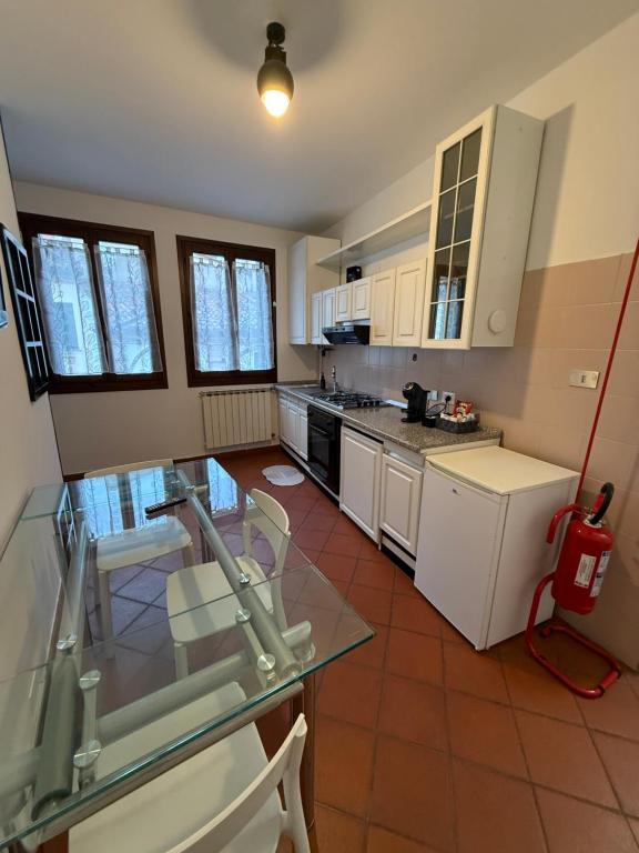 una cucina con armadi bianchi e ripiano in vetro di City Flowers a Rovigo