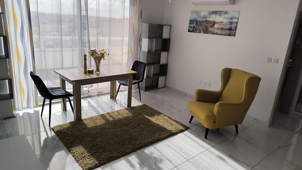 een woonkamer met een tafel en een gele stoel bij Large Terrace with Valletta Views in Il-Gżira