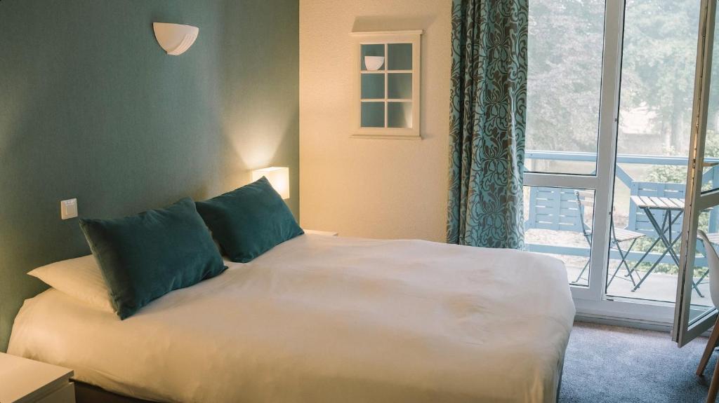 een slaapkamer met een bed en een raam met een balkon bij Hotel Aigue Marine in Tréguier