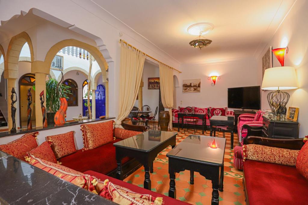 un salon avec des canapés rouges et une télévision dans l'établissement Riad Salmiya Dune, à Essaouira