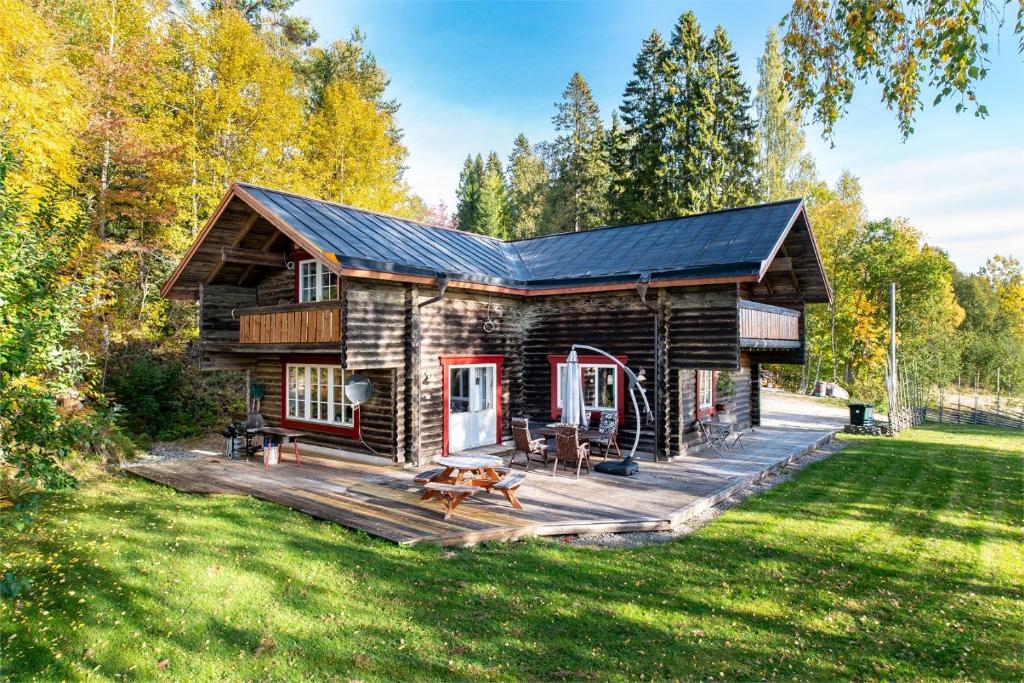 a log cabin with a deck in the grass at Luxurious Log House - Gränsfors 354 in Bergsjö