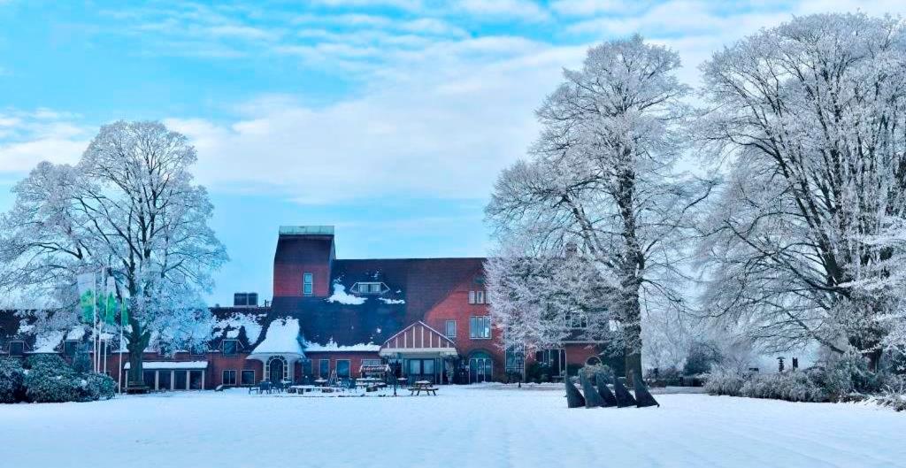 een groot rood huis met sneeuw op de grond bij Landgoed De Wilmersberg in De Lutte