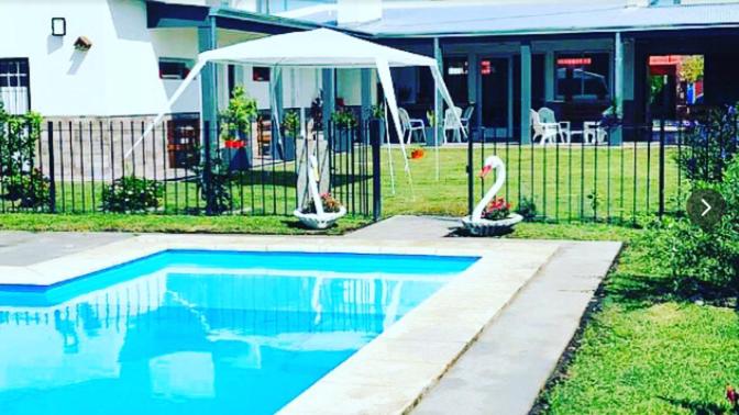 einen Pool vor einem Haus mit Sonnenschirm in der Unterkunft Quinta Altos del Prado in San Nicolás de los Arroyos