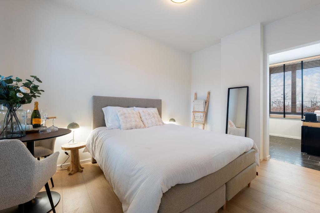 een slaapkamer met een groot wit bed en een stoel bij Huys van Haeghe in Zoutleeuw