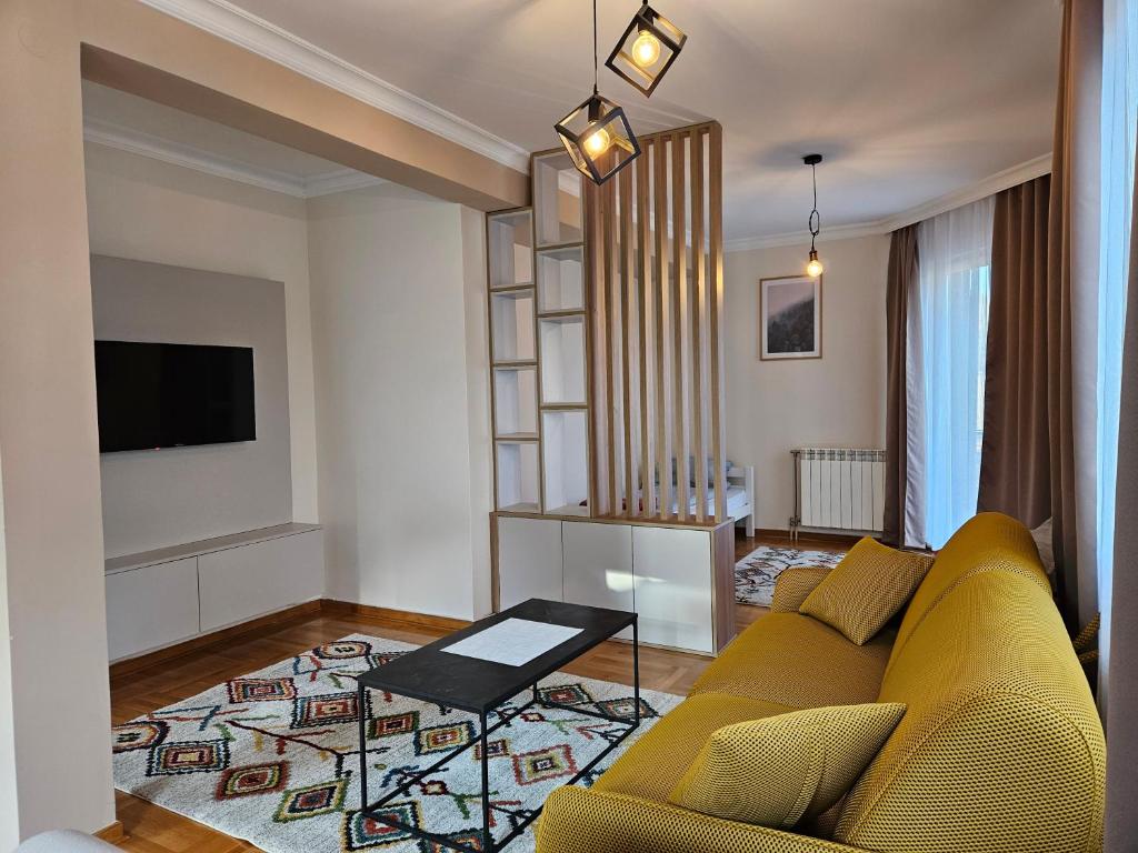 een woonkamer met een gele bank en een tv bij Velike Šume Apartment in Pale