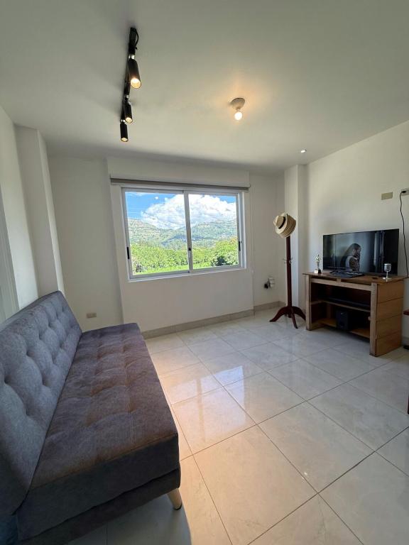 ein Wohnzimmer mit Couch und großem Fenster in der Unterkunft Quiet Haven Terrace with BBQ Hammock in Vilcabamba