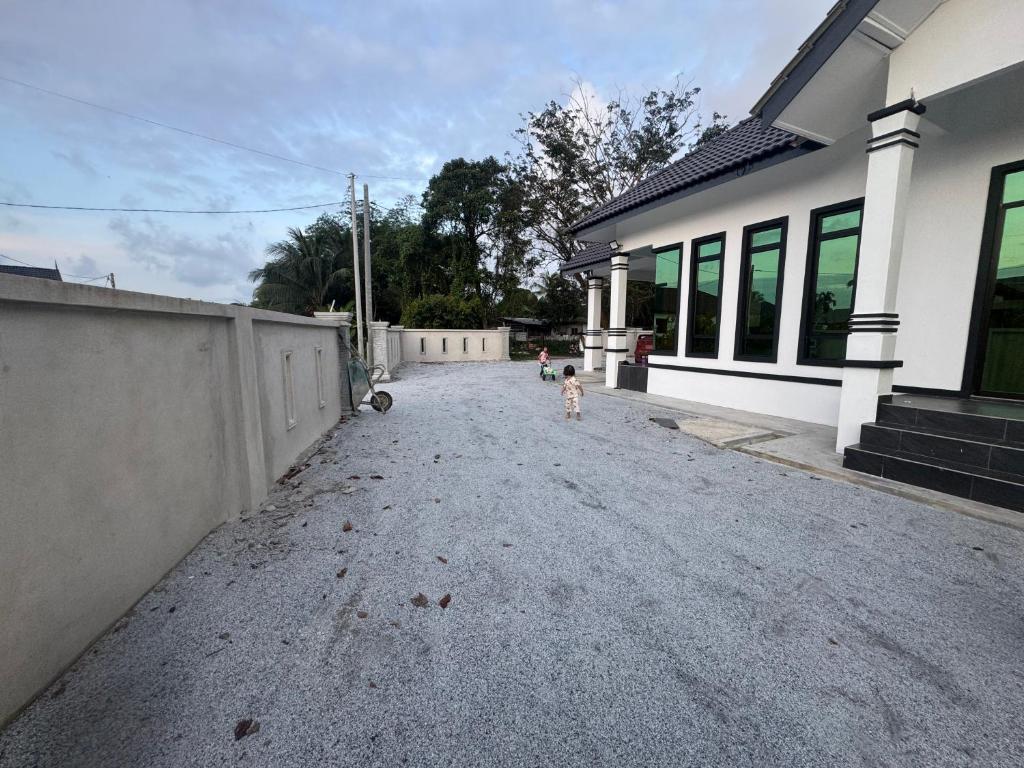 Ein kleines Kind steht mitten auf einer Einfahrt. in der Unterkunft HomestayDino in Kuala Terengganu