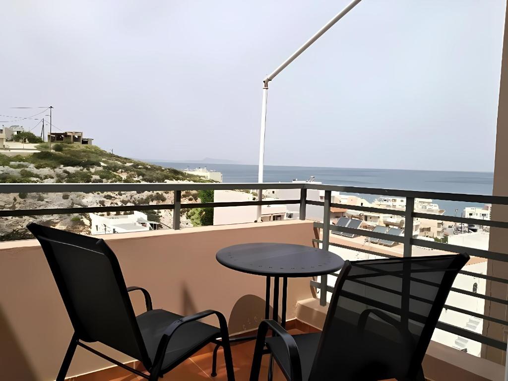 a balcony with chairs and a table and the ocean at Panoramic View Boutique Suite in Rethymno