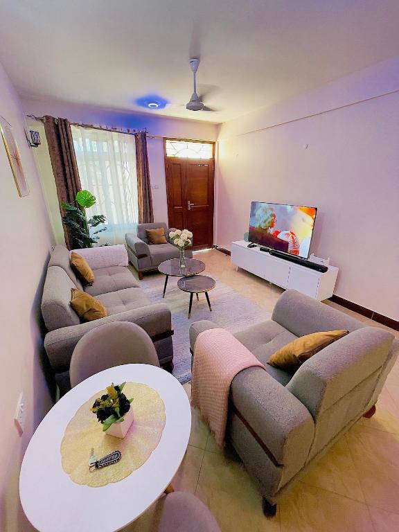 a living room with couches and a flat screen tv at Lucia Homes & Stays in Dodoma