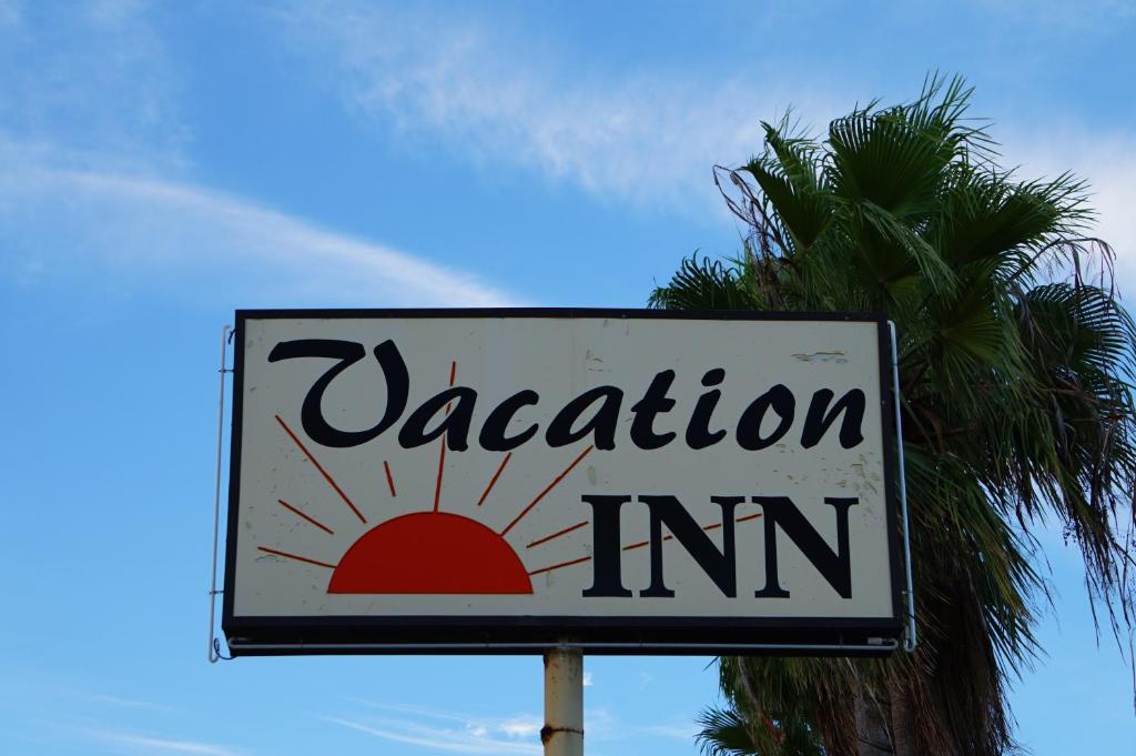 a vacation inn sign in front of a palm tree at Vacation Inn Motel in Fort Lauderdale
