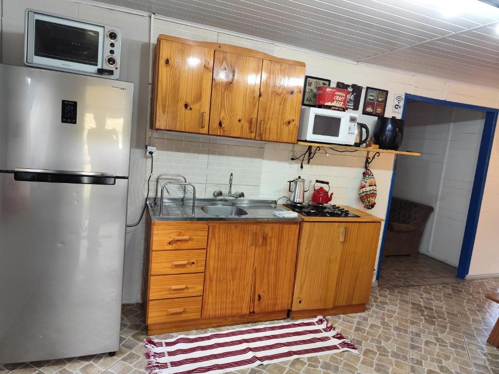 une cuisine avec des armoires en bois et un réfrigérateur en acier inoxydable dans l'établissement Sossego na Serra Catarinense - Casa em Lages, à Lages