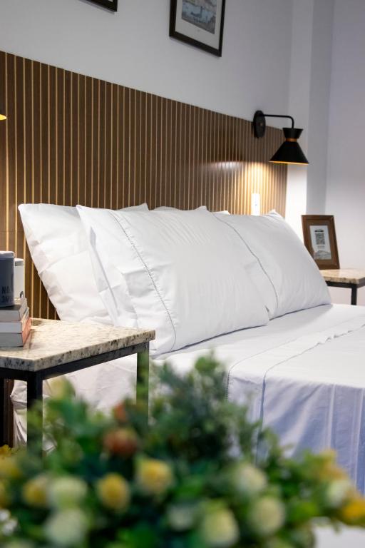 a bed with a white pillow and a table at Centro Histórico com Garagem - Studio Petrópolis in Petrópolis