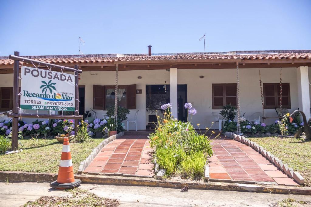 a house with a sign in front of it at Pousada recanto do mar torres Itapeva norte in Torres