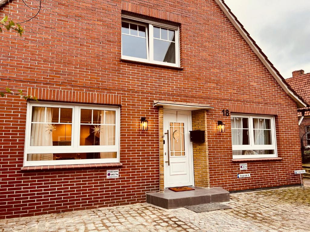 een stenen huis met een witte deur en ramen bij Ferienwohnung auf dem Berg in Bad Bentheim