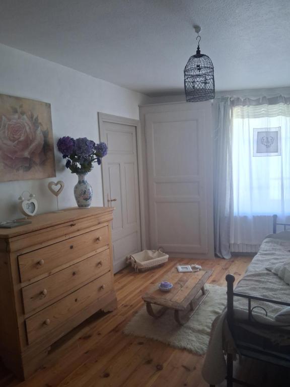 een slaapkamer met een commode en een vaas met paarse bloemen. bij Chambres d'hôtes in Échandelys