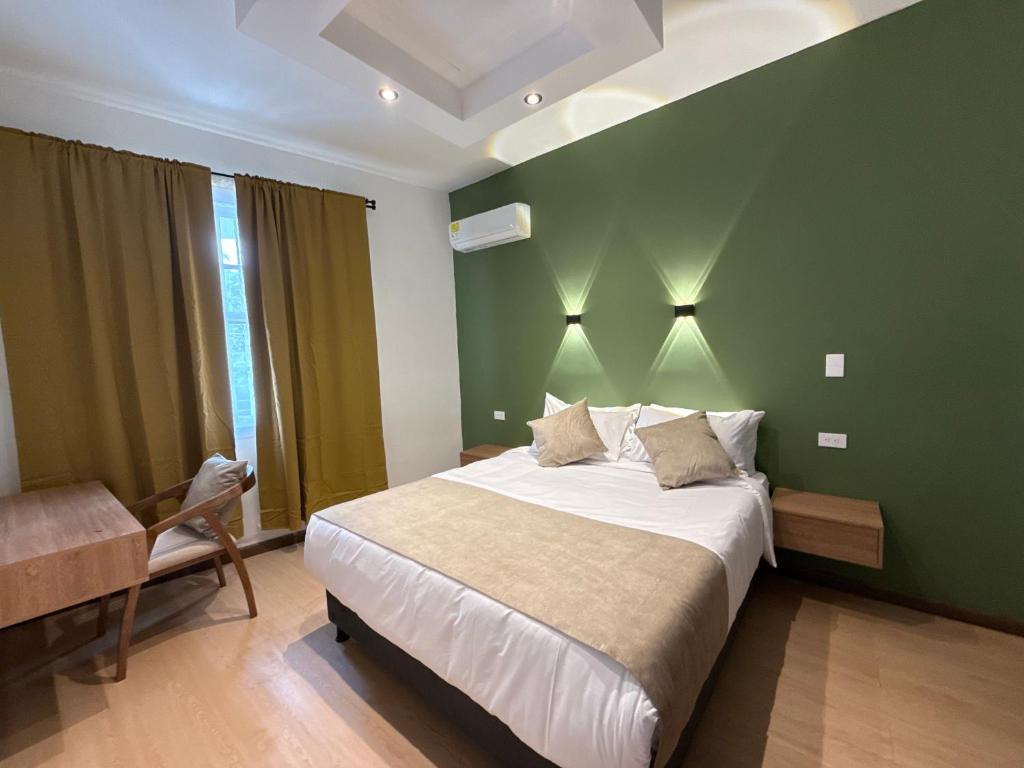 a bedroom with a large bed and a green wall at Hotel B&B Nativo Peñón in Cali