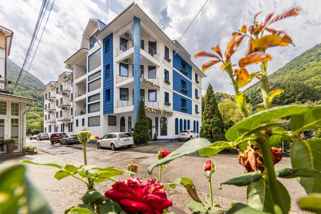 a building with blue trim and flowers in front of it at Hotel Golden Spirit in Băile Herculane