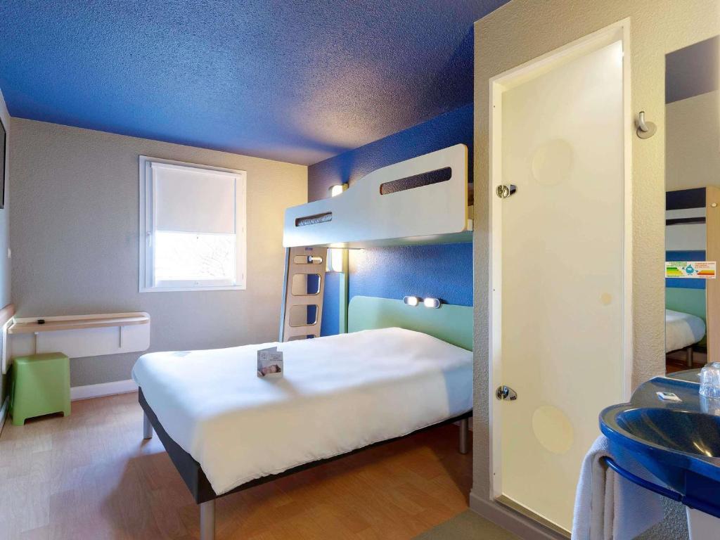 een slaapkamer met een stapelbed en een blauw plafond bij ibis budget La Roche Sur Yon Vendespace in Mouilleron-le-Captif